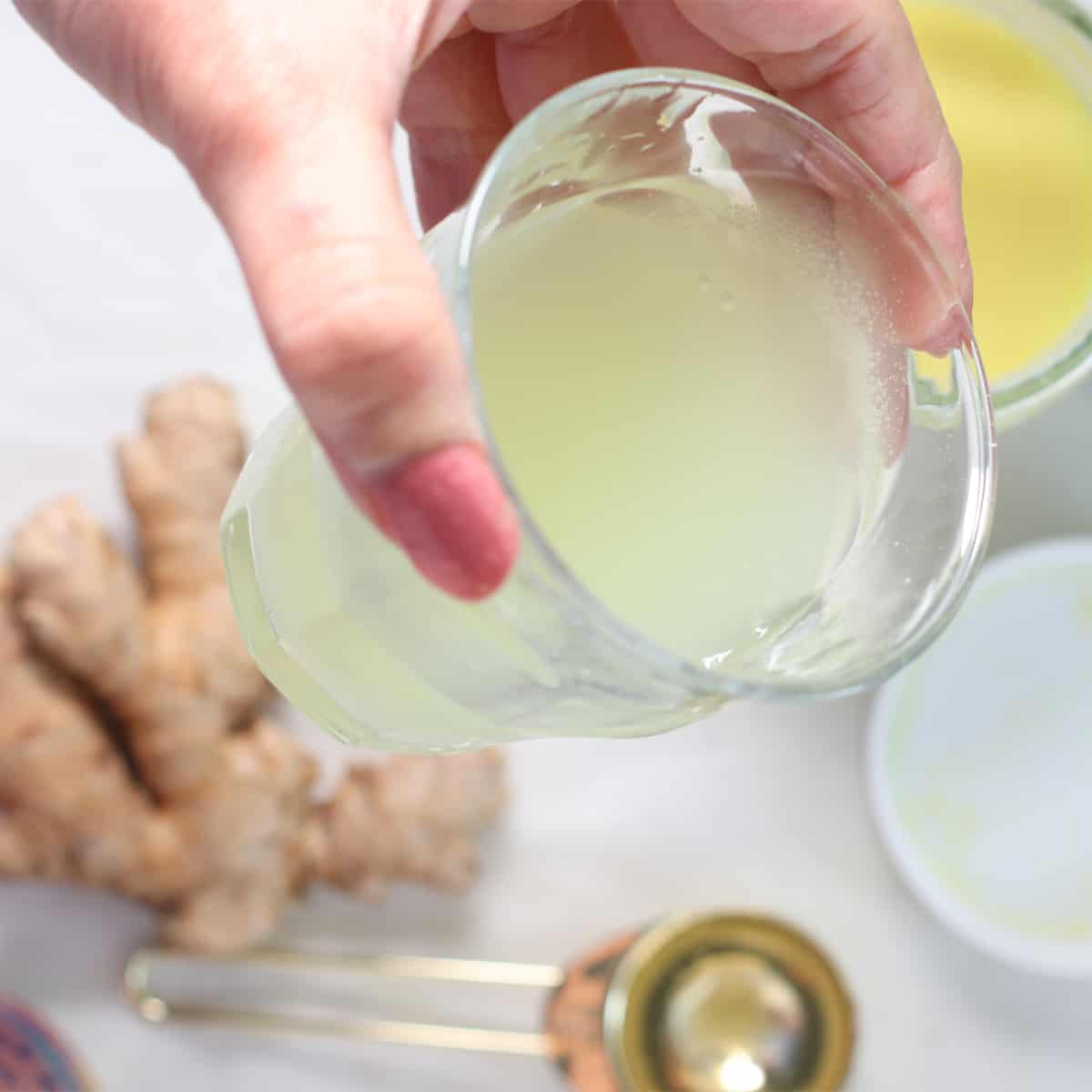 Ginger Juice in a glass held by hand.