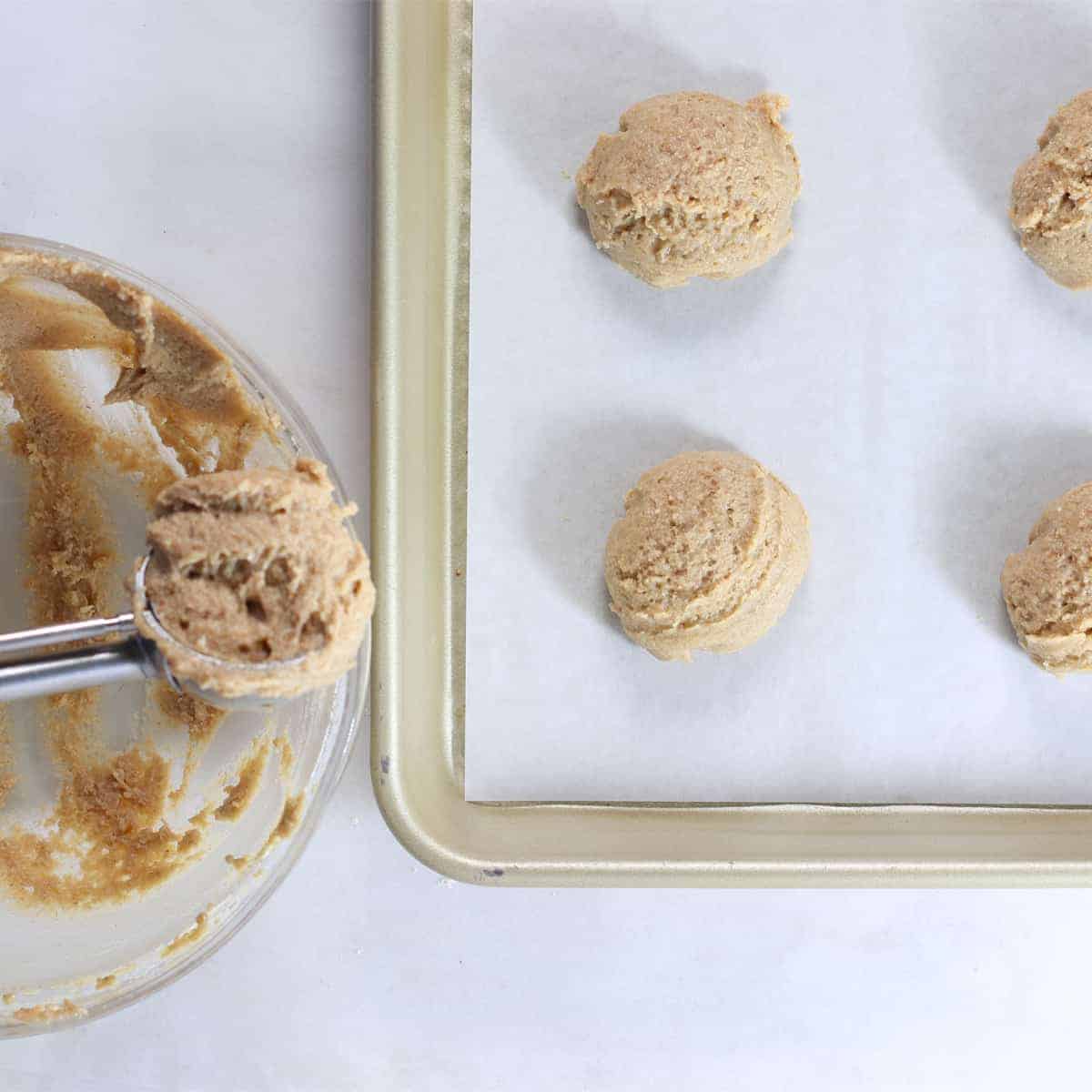 scoops of sugar cookie batter lined on a pan.