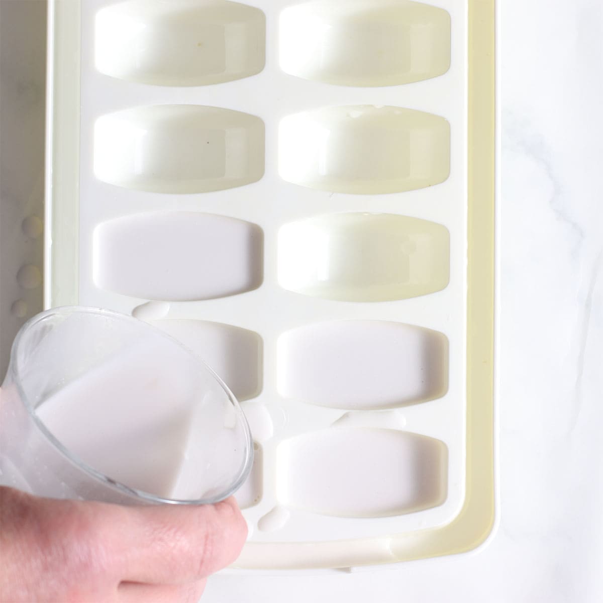 pouring milk into ice cube tray.