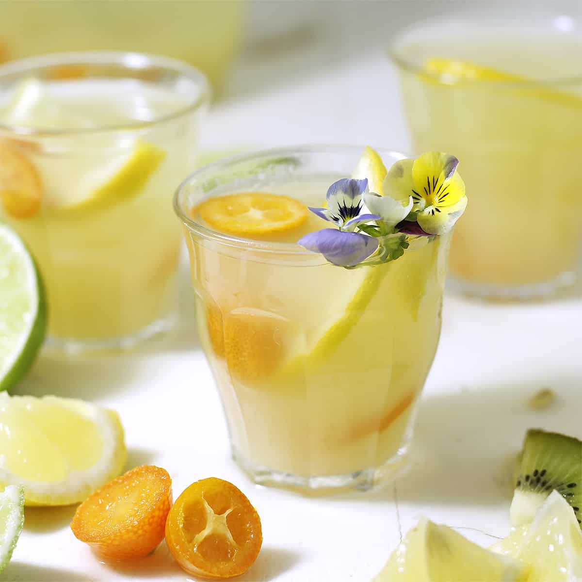 a glass of lemonade with kumquats and a flower