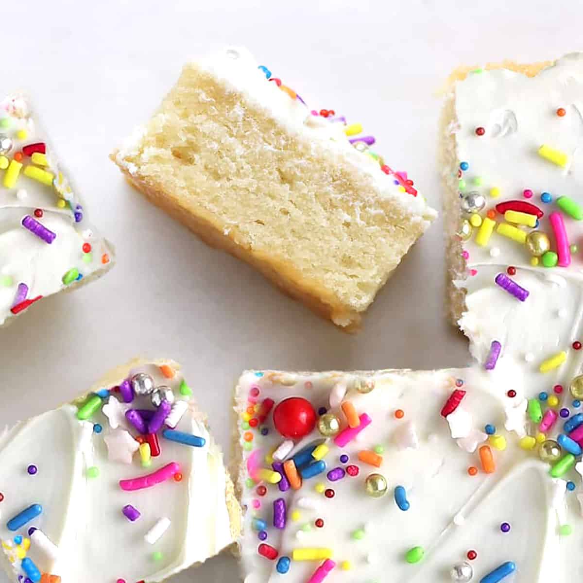 overhead slice of vanilla cake with white frosting and sprinkles.
