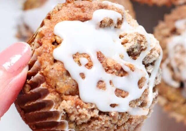 pumpkin muffins with glaze and hand holding one.