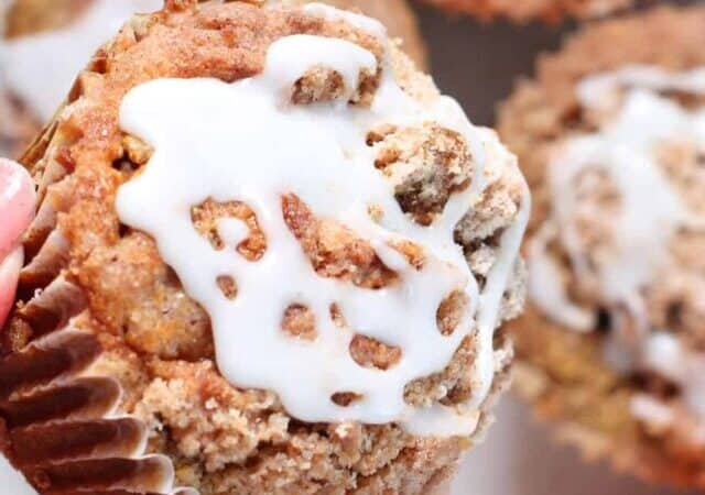 pumpkin muffins with glaze and hand holding one.