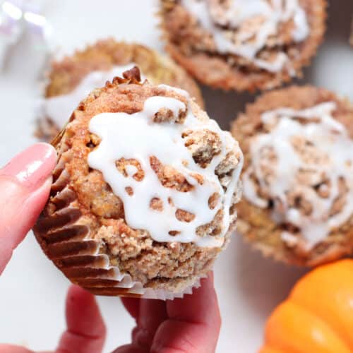 pumpkin muffins with glaze and hand holding one.