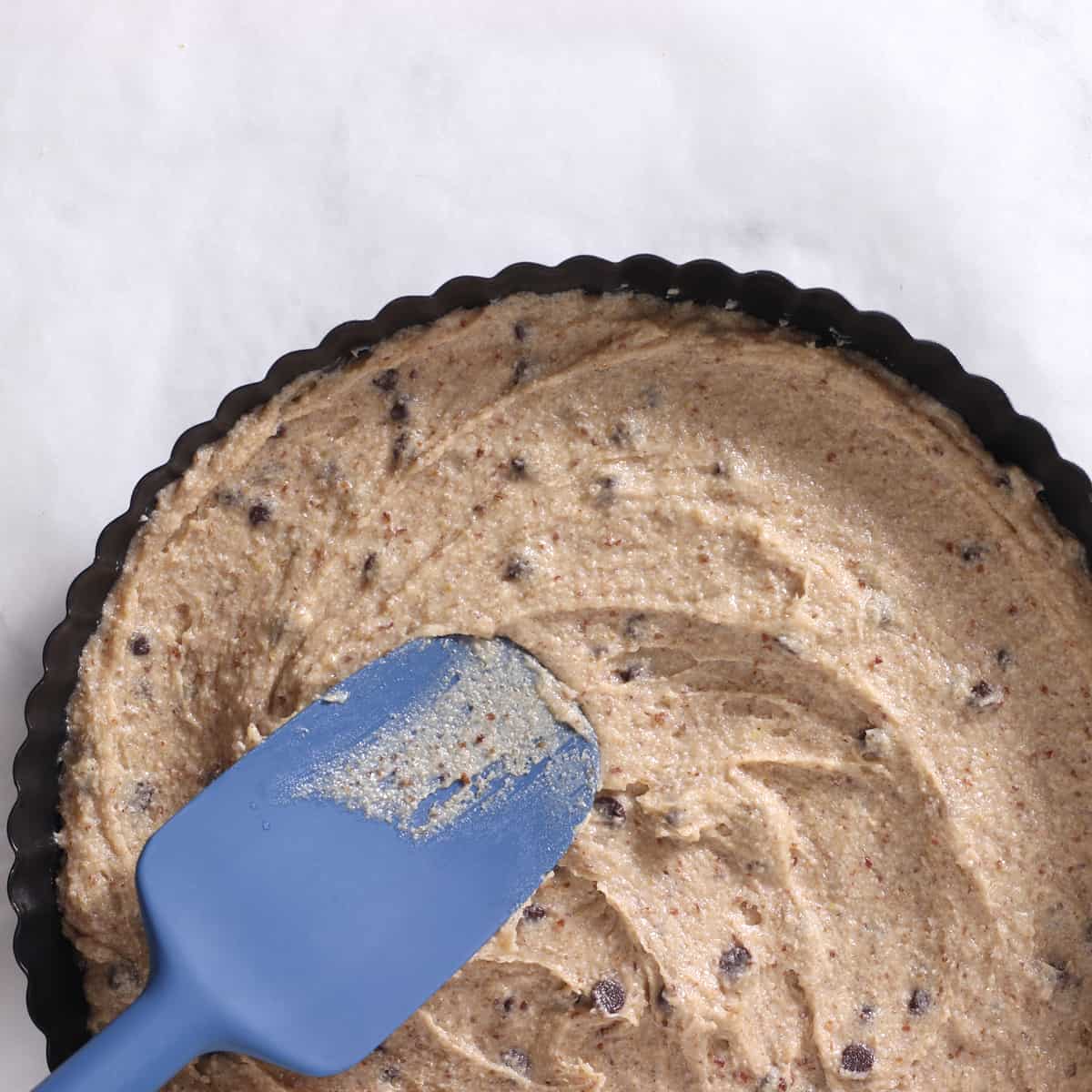 cookie cake batter in a pan with spatula