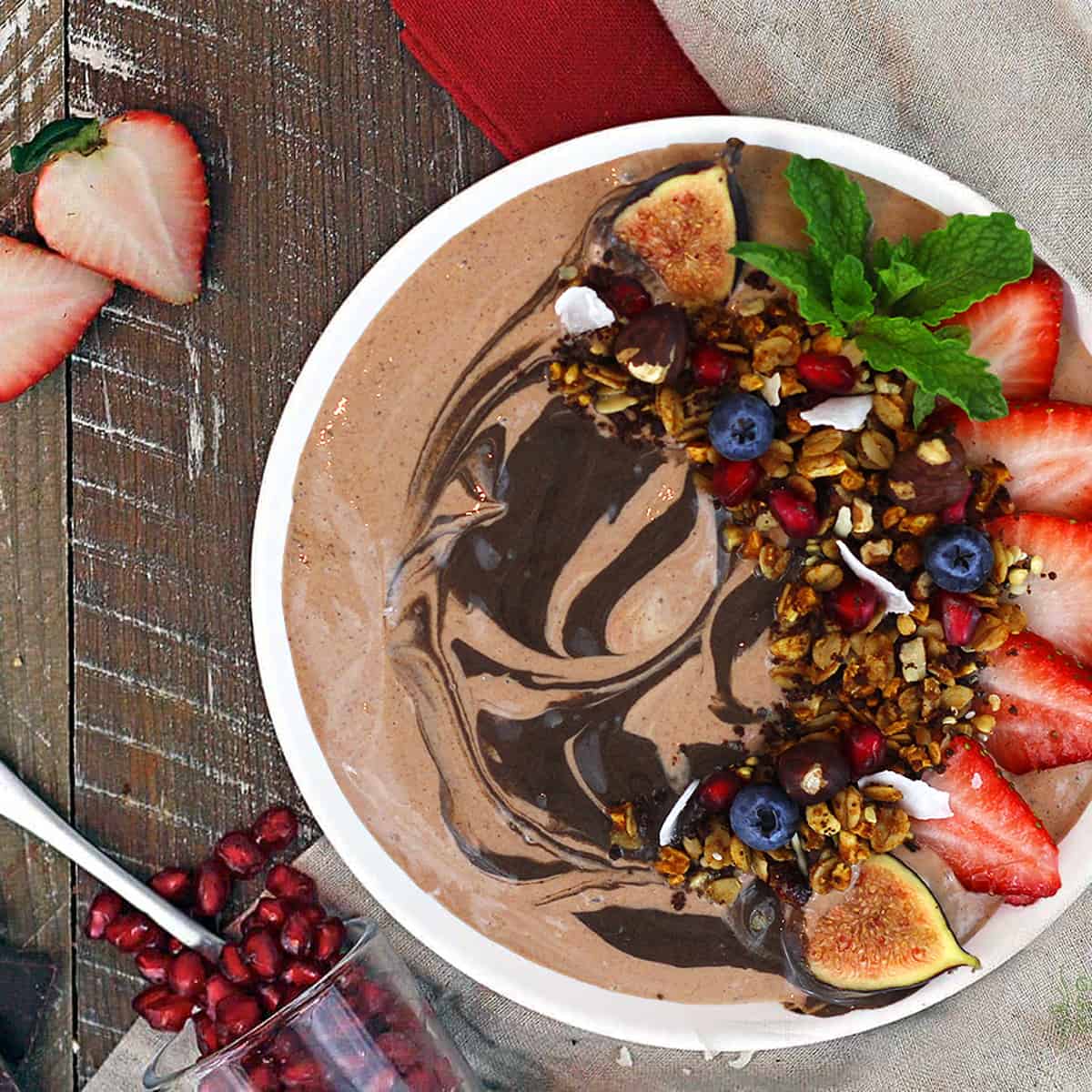 overhead view of a chocolate hazelnut smoothie bowl topped with fruit