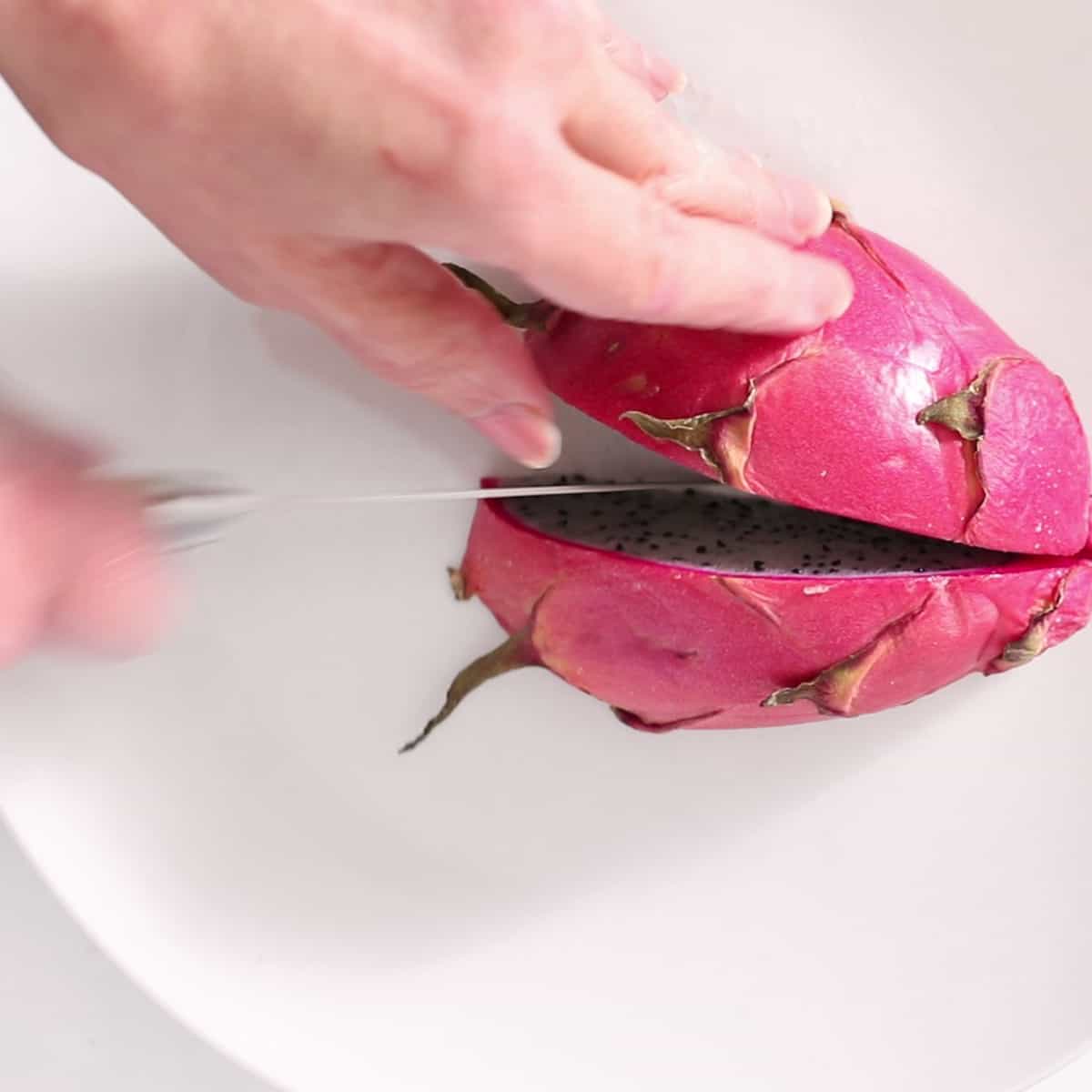 hands slicing a dragon fruit