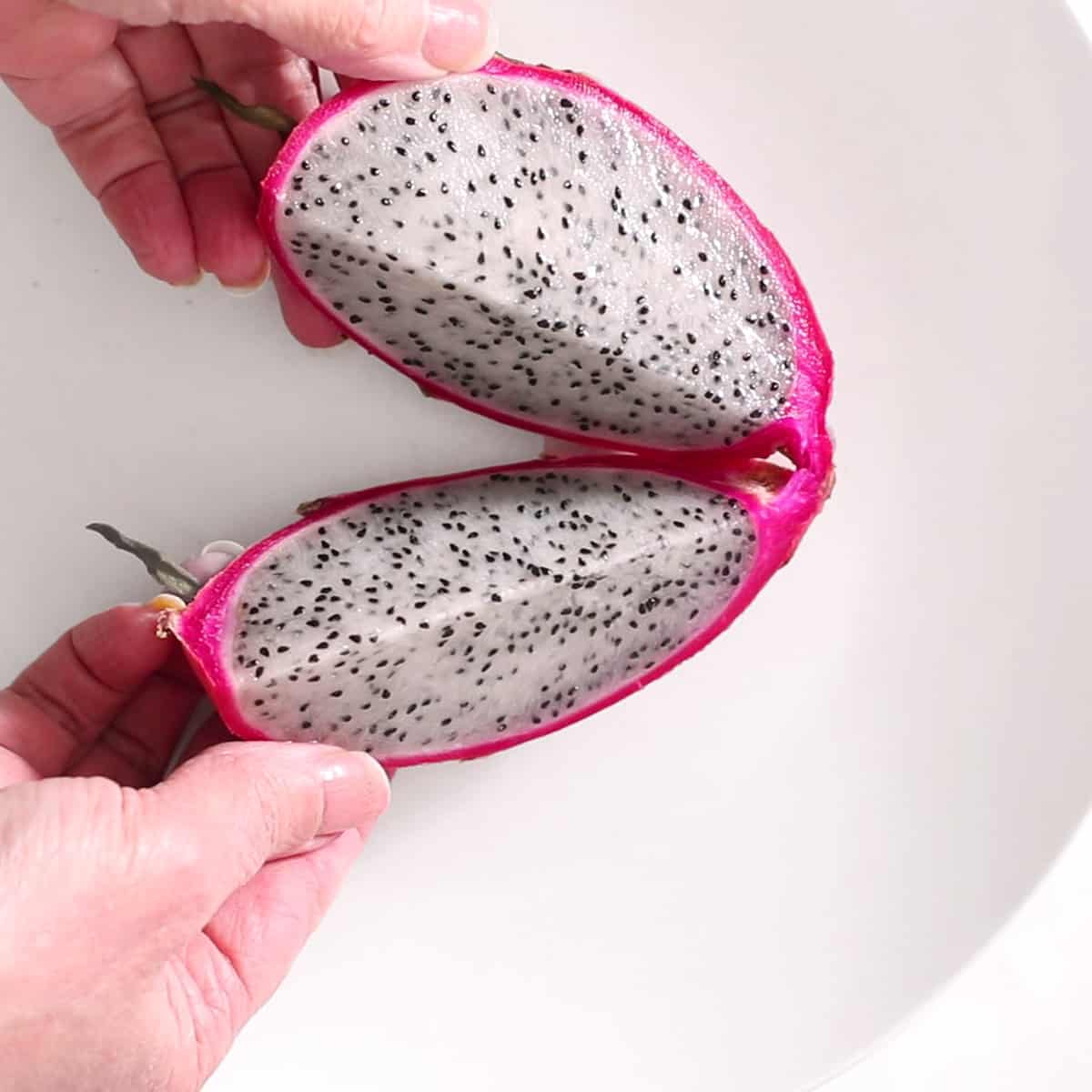 hands holding sliced dragon fruit