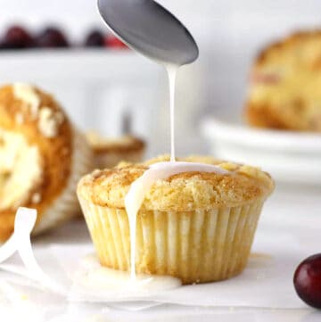 cranberry orange muffins with a spoon drizzling a glaze