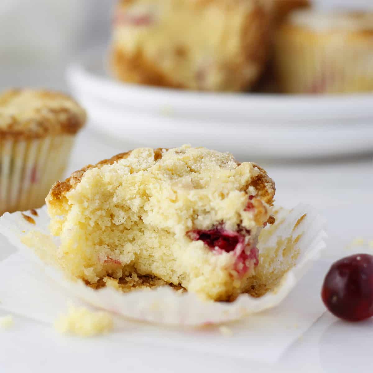 baked cranberry orange muffin with a bite on a dish.