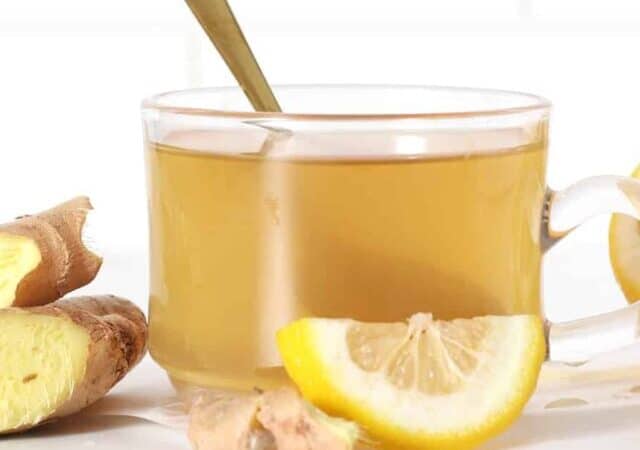 a cup of ginger tea with lemon slices and ginger slices