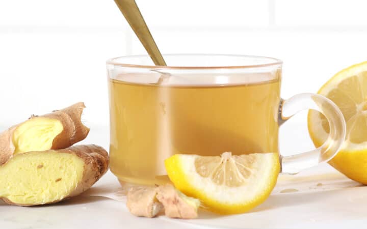 a cup of ginger tea with lemon slices and ginger slices