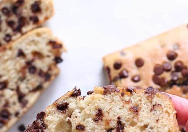 a hand holding a slice of chocolate chip cake