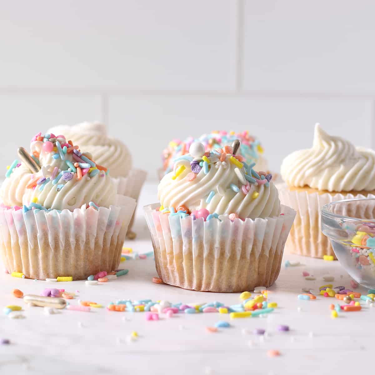 a row of frosted and sprinkled cupcakes