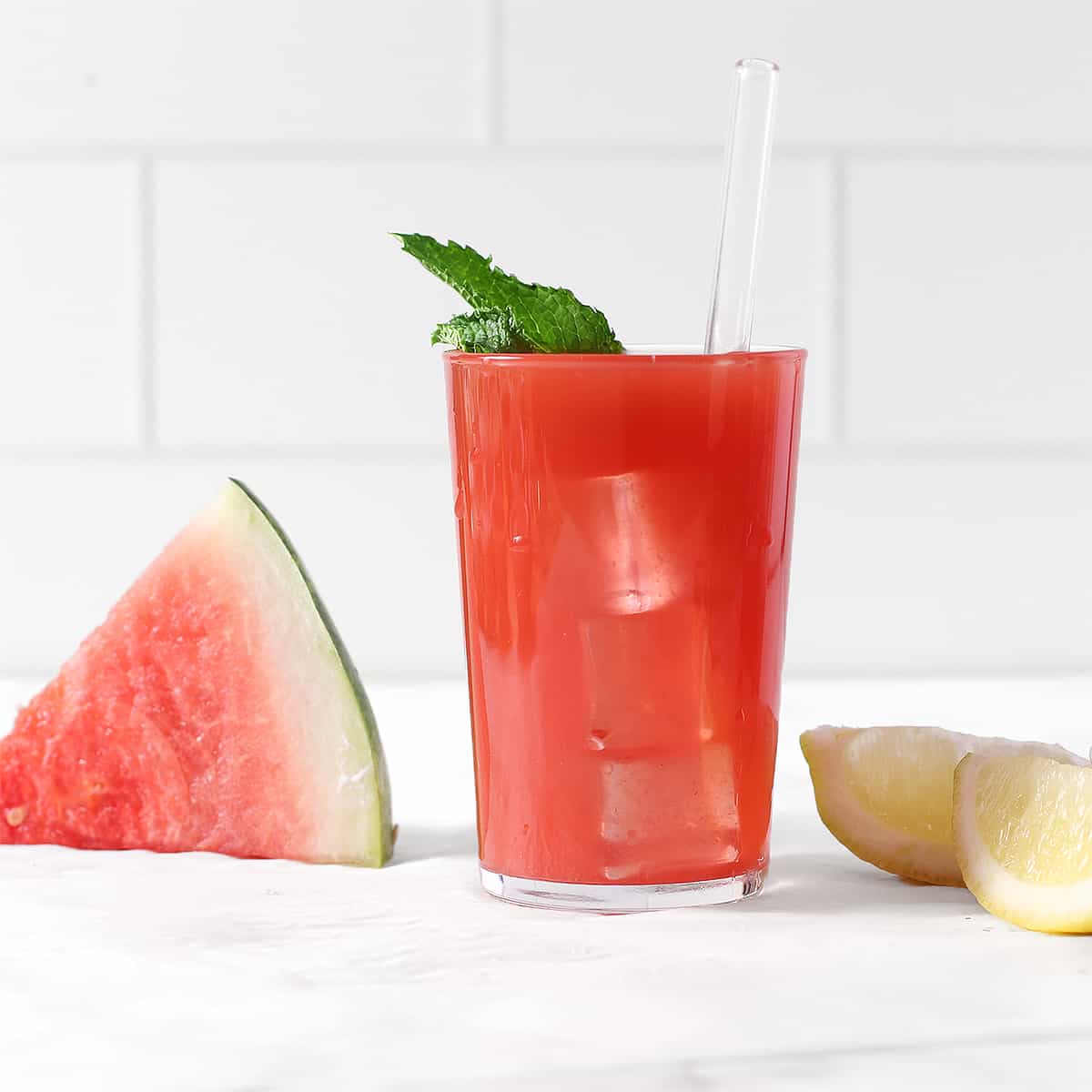 a glass of watermelon juice with lime leaf
