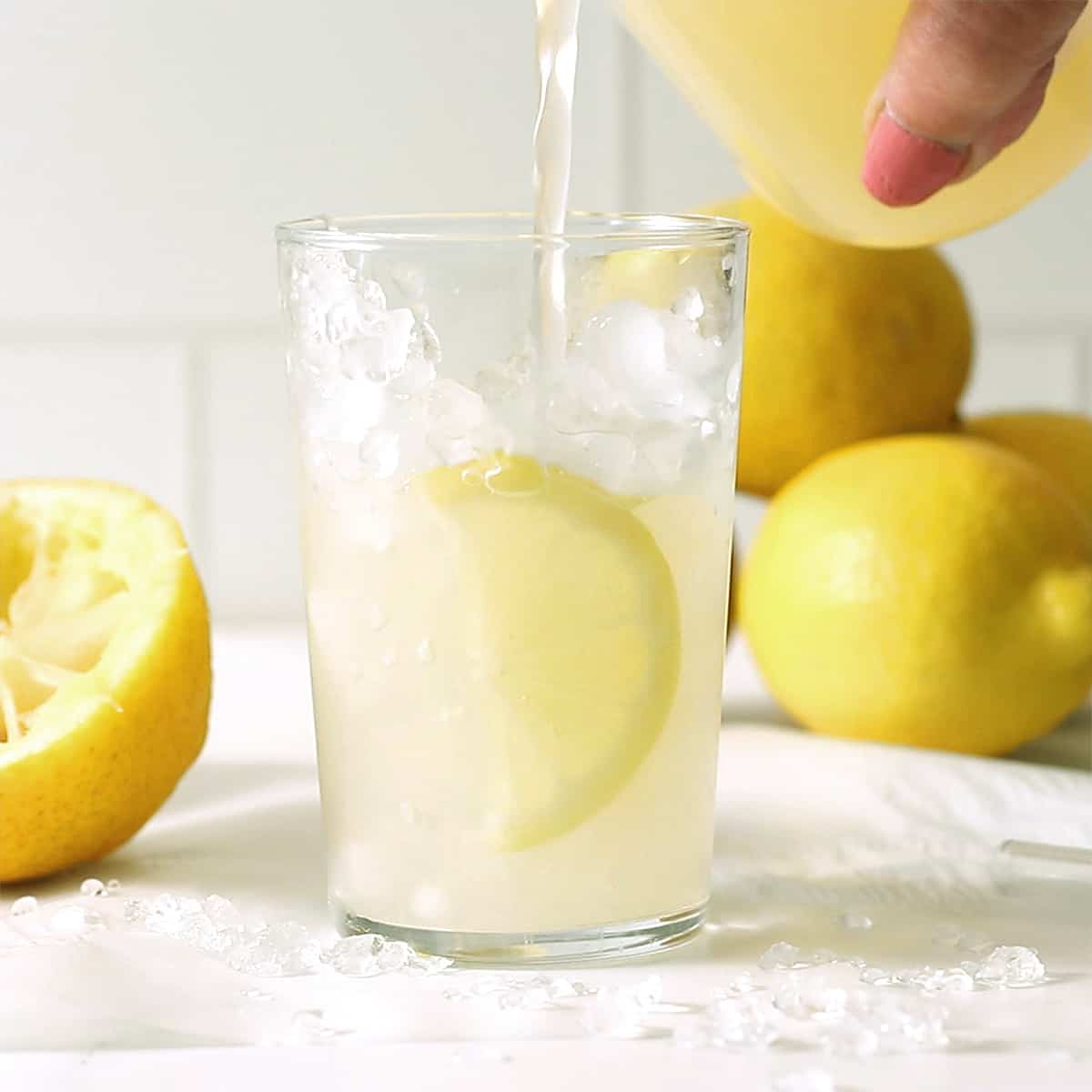 pouring lemonade into a glass of ice