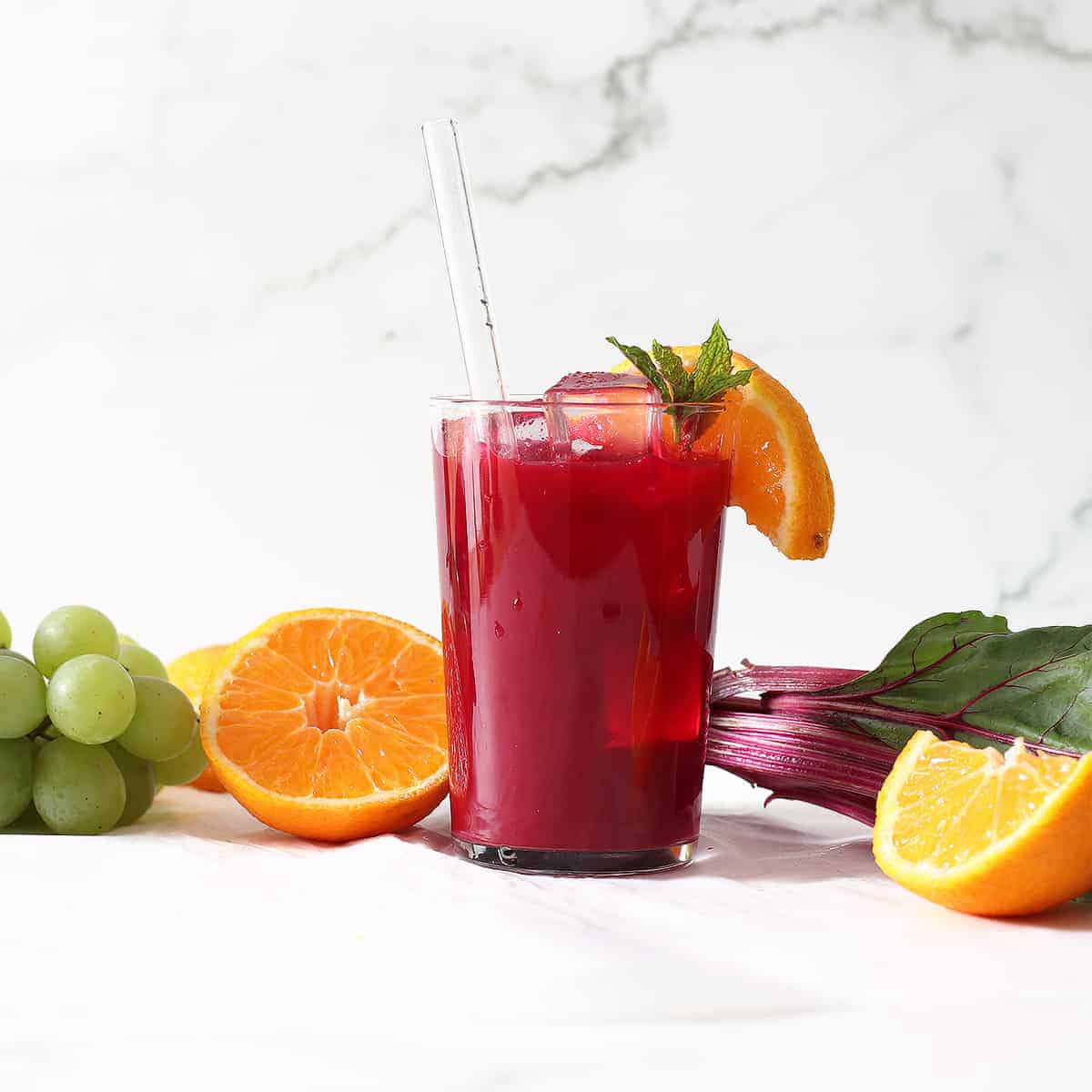 beet juice in a glass with a glass straw and orange slice.