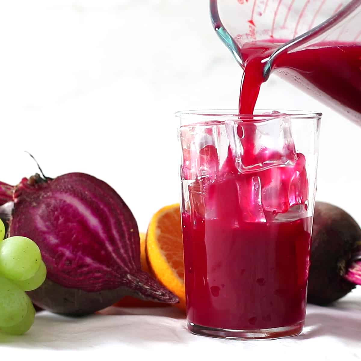 pouring beet juice over ice in a glass.