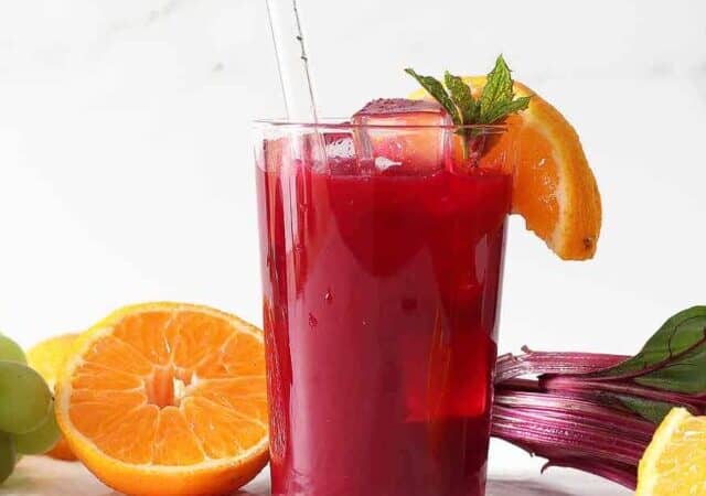 beet juice in a glass with a glass straw and orange slice.