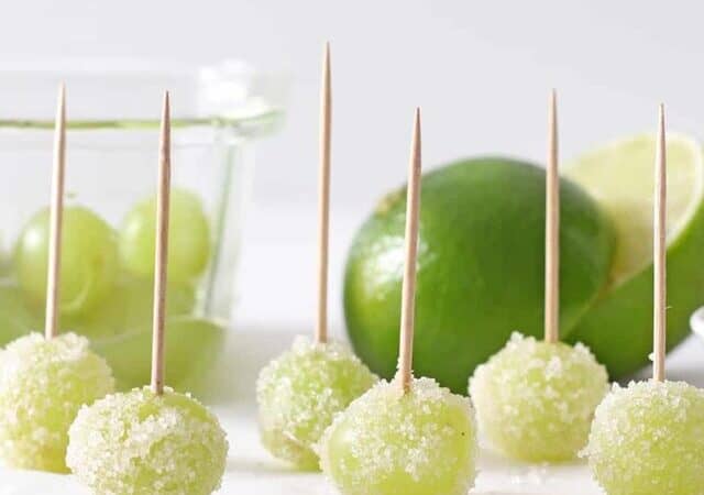 a row of sour patch frozen grapes on toothpicks.