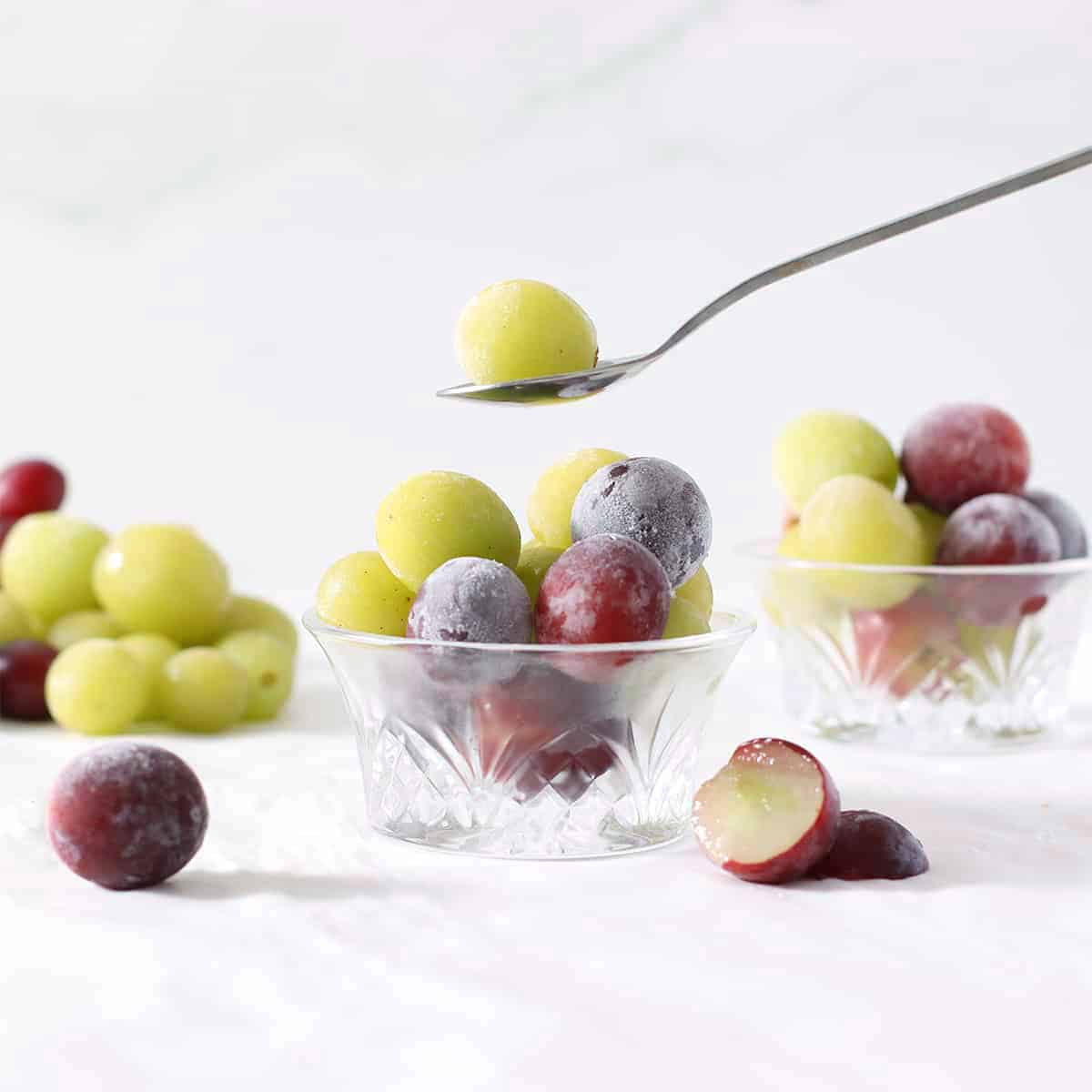 frozen grapes in a bowl with a spoon holding one above it.