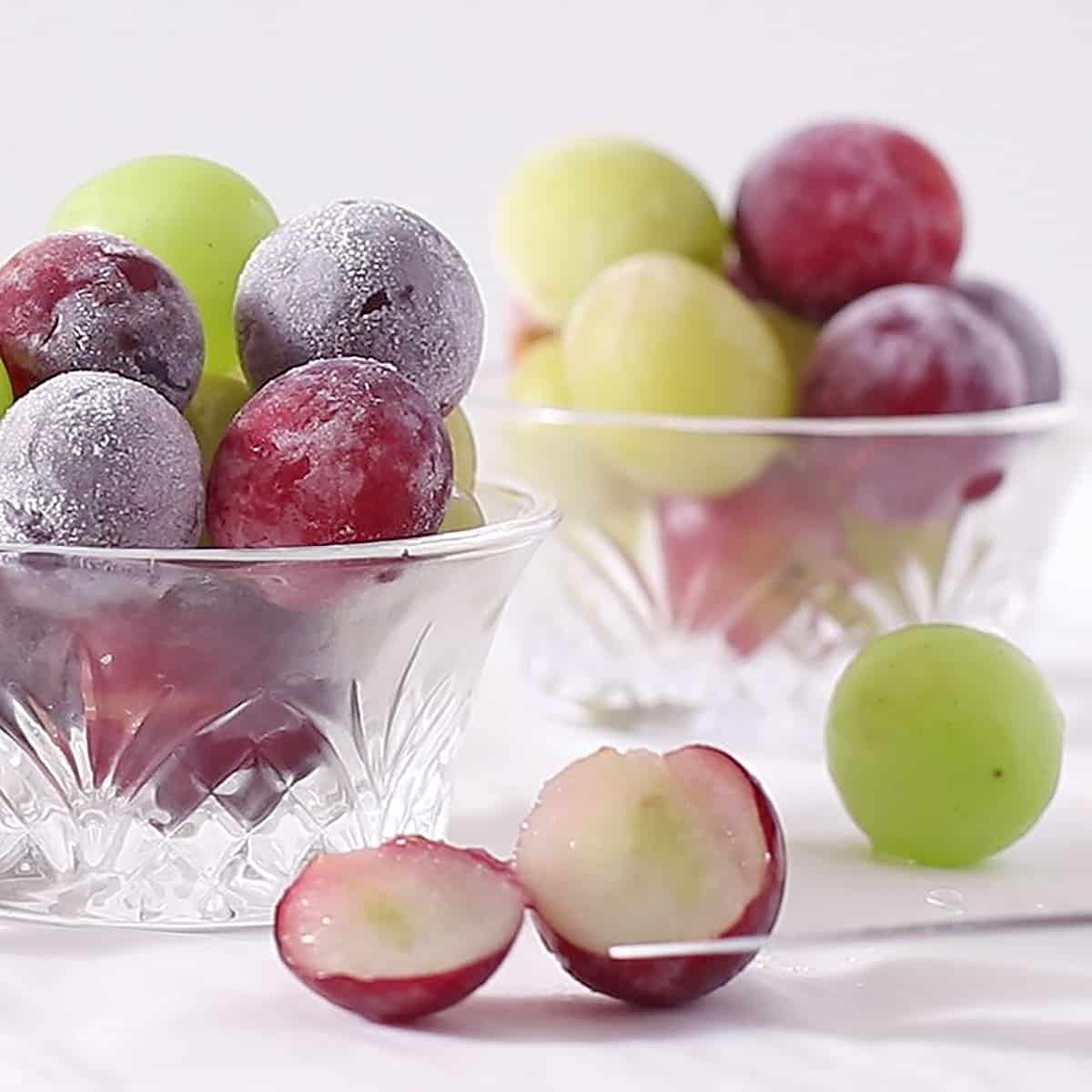 a frozen grape sliced with a knife tip near it.