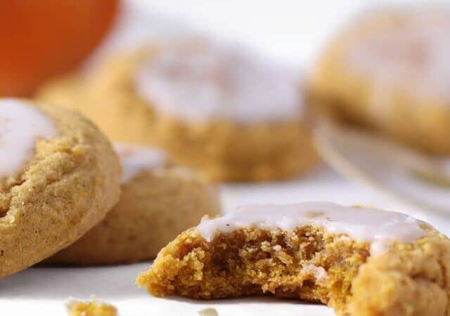 pumpkin sugar cookies with glaze and a bite.