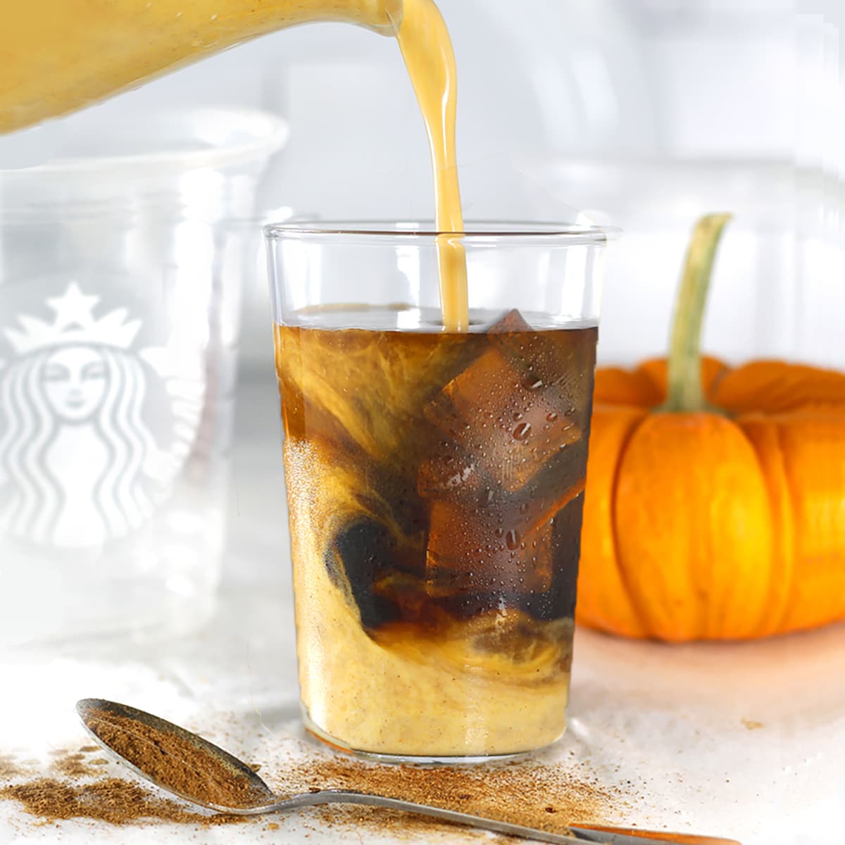 iced pumpkin spice latte with a pour of milk.