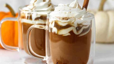 pumpkin spice latte in two mugs with whipped cream.