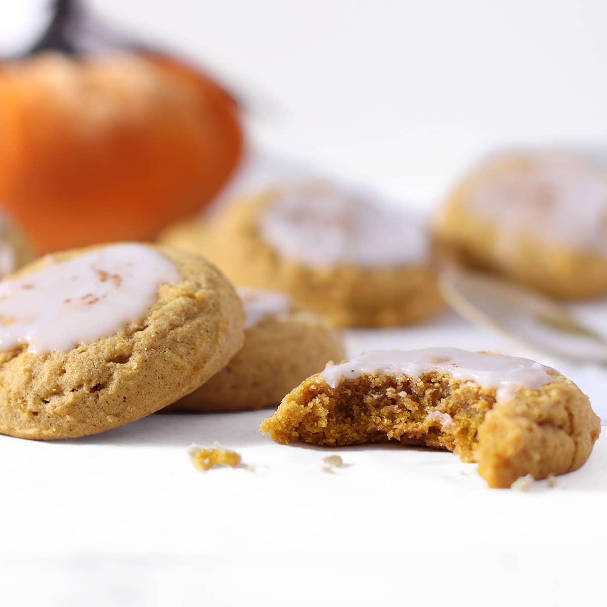 pumpkin sugar cookies with glaze and a bite.