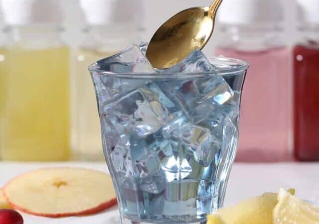 blue homemade electrolyte drink in a glass of ice.