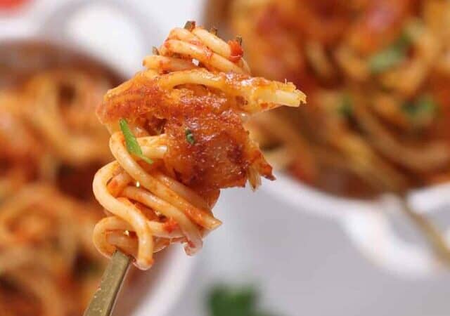 a forkful of fried spaghetti with crispy melted cheese.