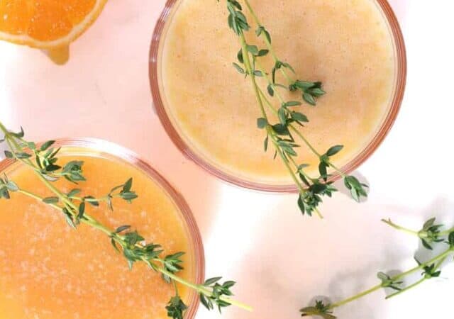 overhead of orange juice with thyme.