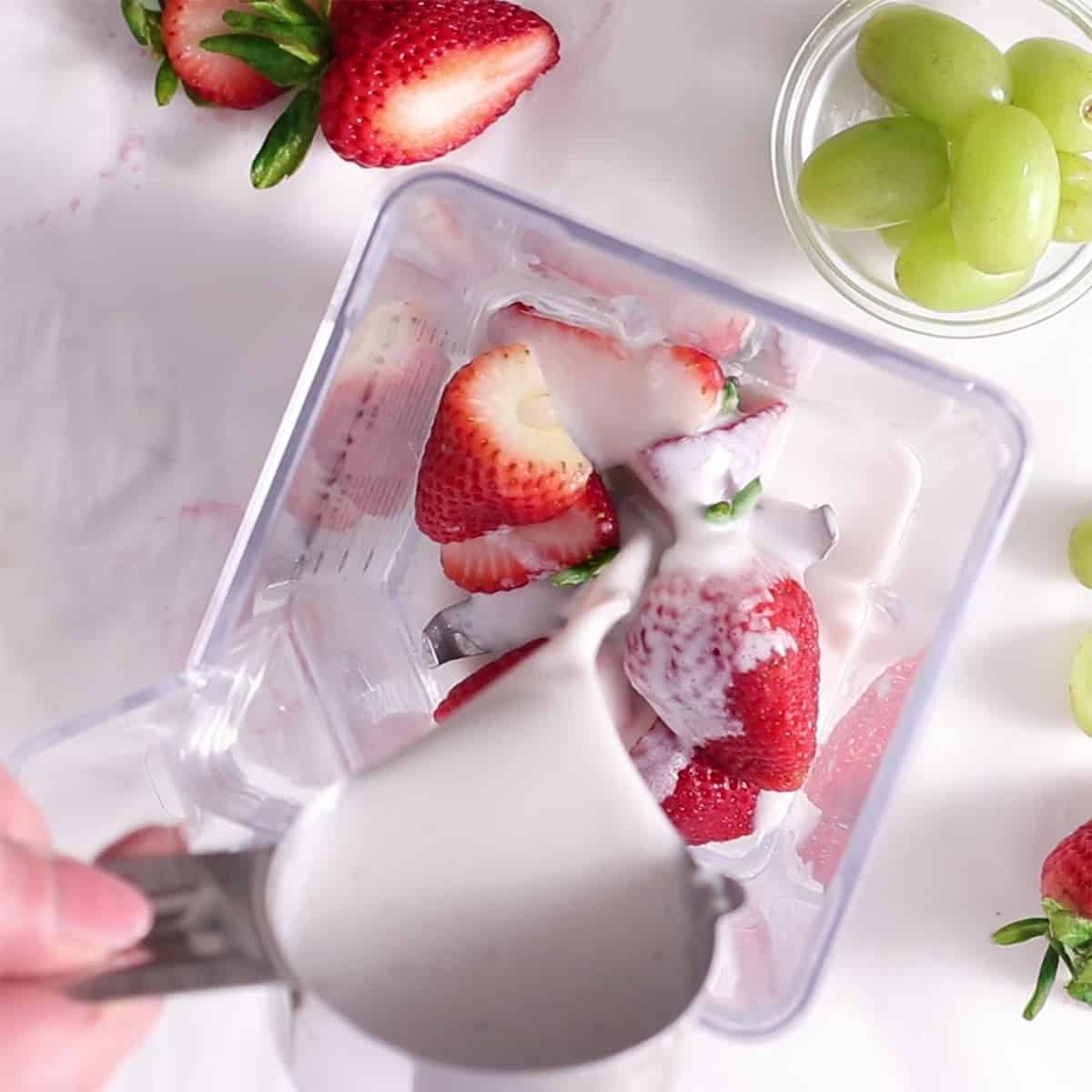 strawberries and milk in a blender jar.