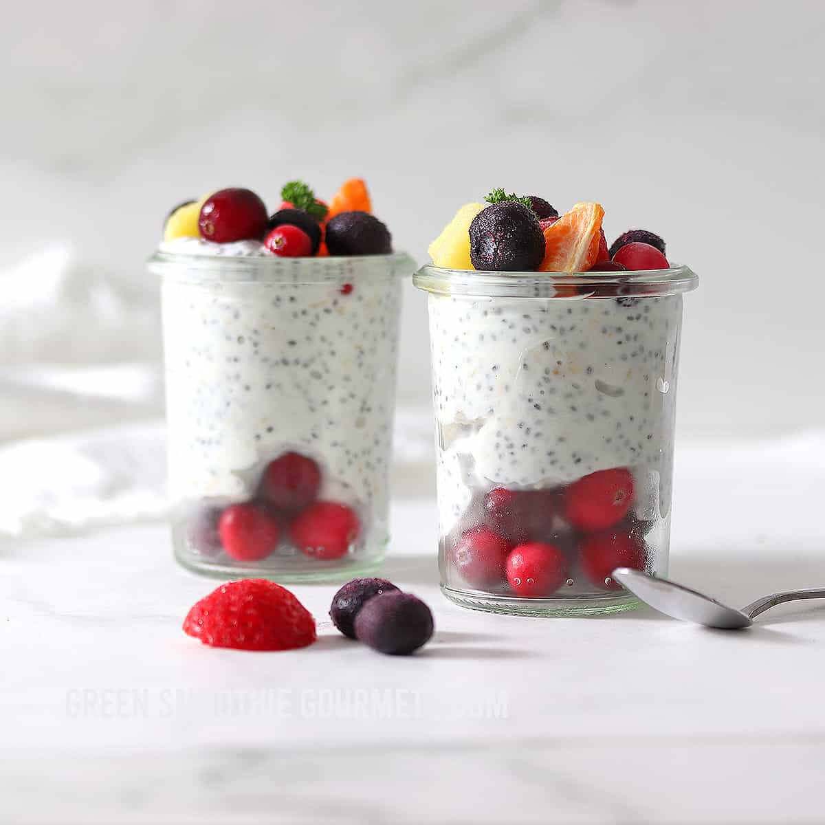 high protein overnight oats in two glasses with fruit.
