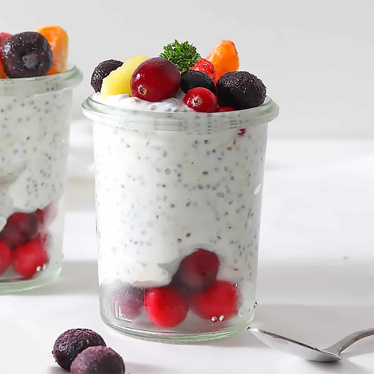 high protein overnight oats in two glasses with fruit.