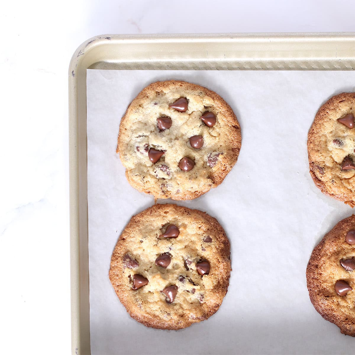 thin and crispy chocolate chip cookies made with almond flour baked in a pan.