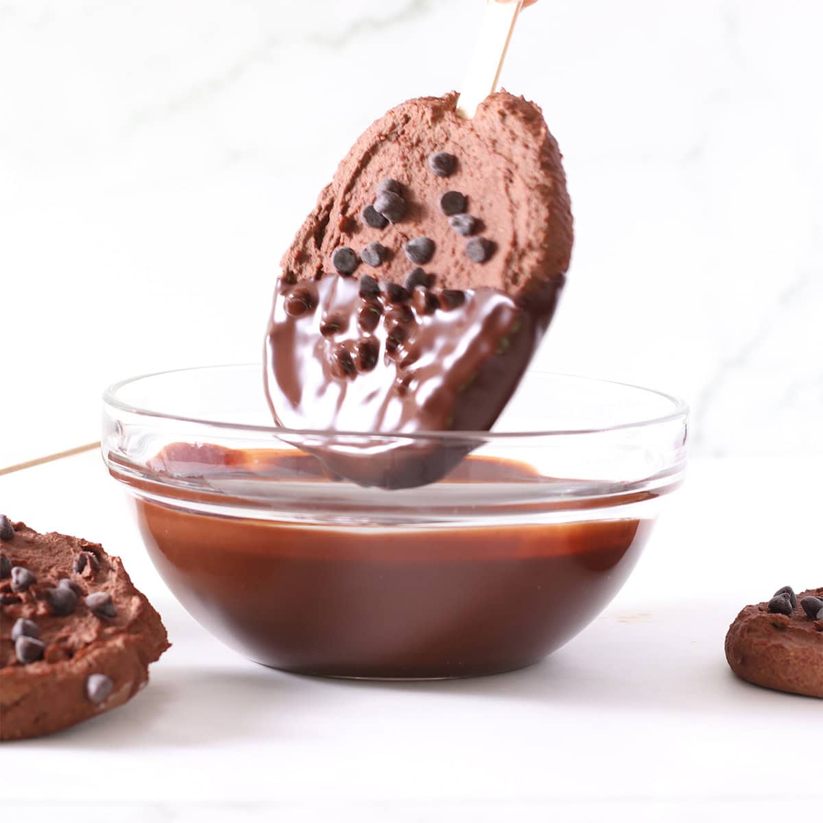 chocolate frozen yogurt pops being dipped.