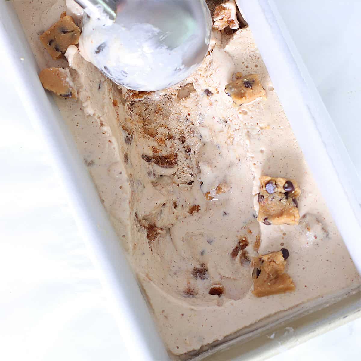 scooping cookie dough frozen yogurt in pan.