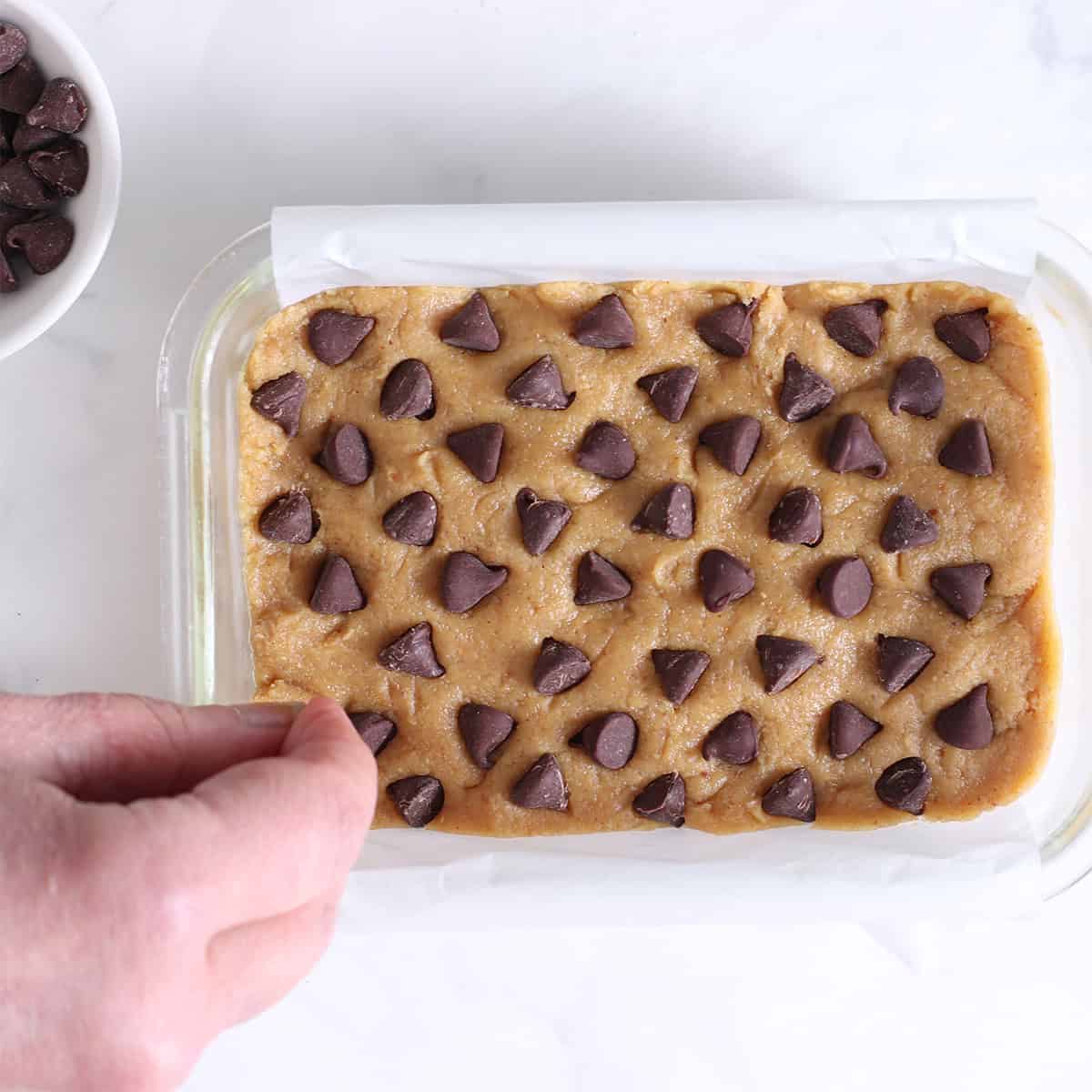 peanut butter cookie dough pressing chocolate chips on top.