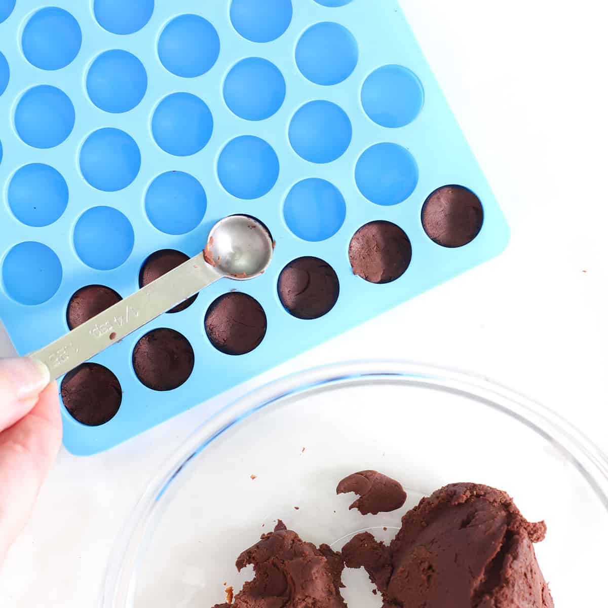 pressing brownie batter into bite mold.